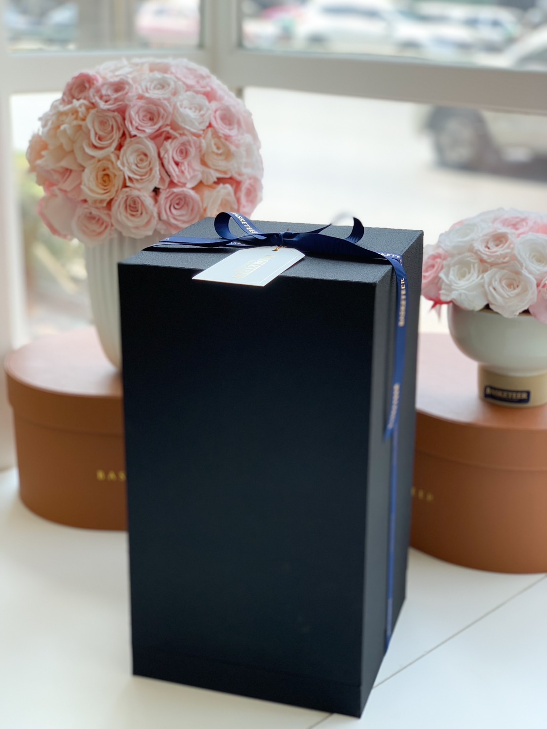 A premium black luxury gift box wrapped with a navy blue ribbon and a gold-accented tag. Perfect for high-end gifting, corporate presents, and special occasions.
