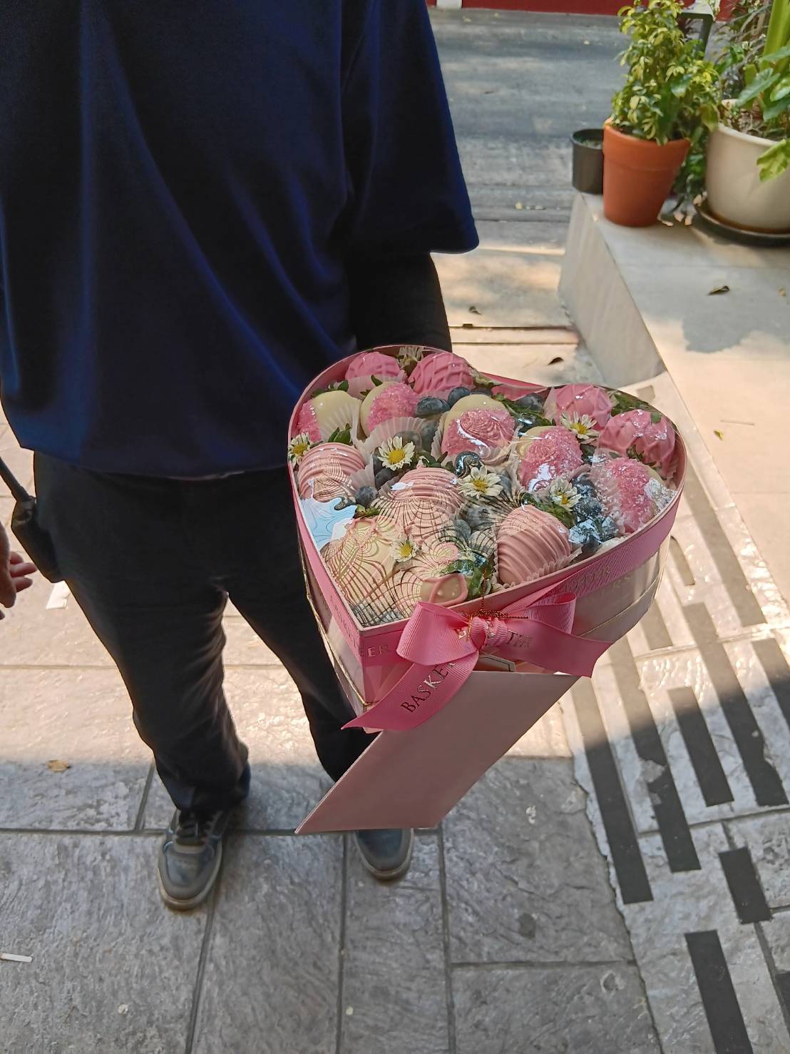A romantic heart-shaped gift box filled with chocolate-dipped strawberries, elegantly decorated with floral accents and wrapped with a satin ribbon.