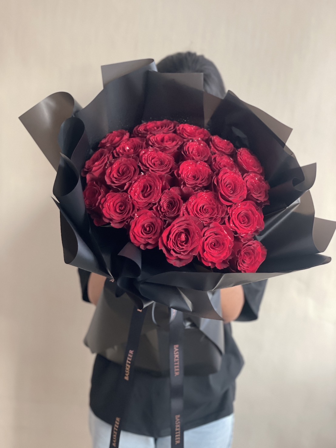 A stunning bouquet of premium red roses, beautifully wrapped in sophisticated black paper, creating a bold and elegant look. Ideal for romantic occasions and special moments.