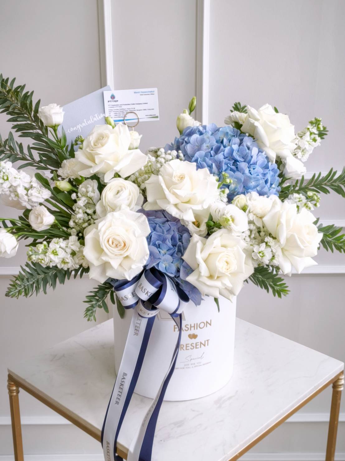 Luxury flower box with white roses, blue hydrangeas, and fresh greenery, tied with white and navy ribbons