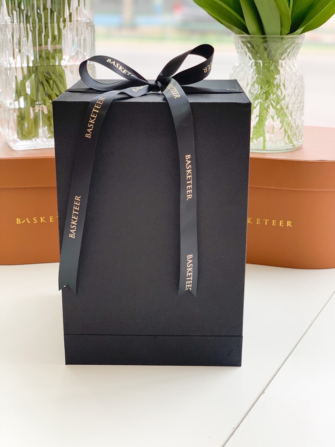 Elegant black gift box with black satin ribbon embossed in gold “Basketeer” – perfect for luxury gift packaging.