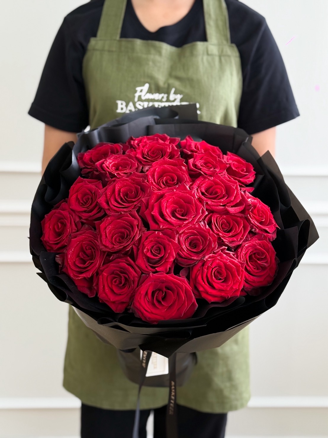 Luxurious bouquet of red roses wrapped in black paper, creating a bold and elegant romantic gift arrangement.