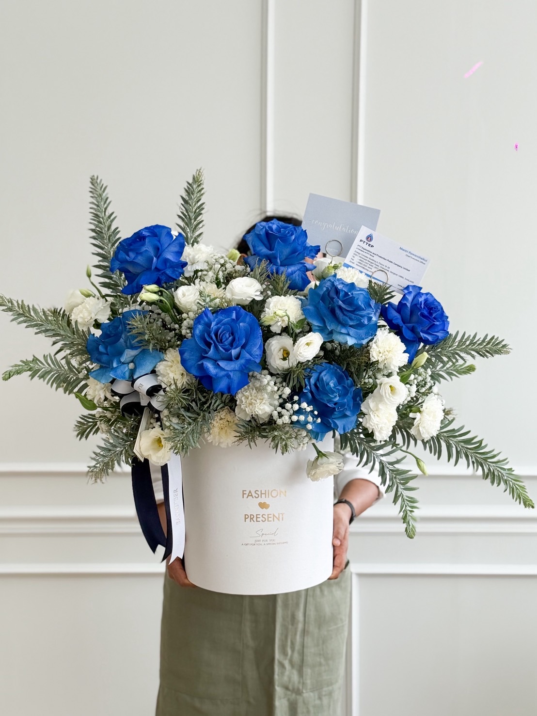 Luxury flower box with blue roses, white roses, lisianthus, and white accent flowers, styled with greenery in a tall round box.