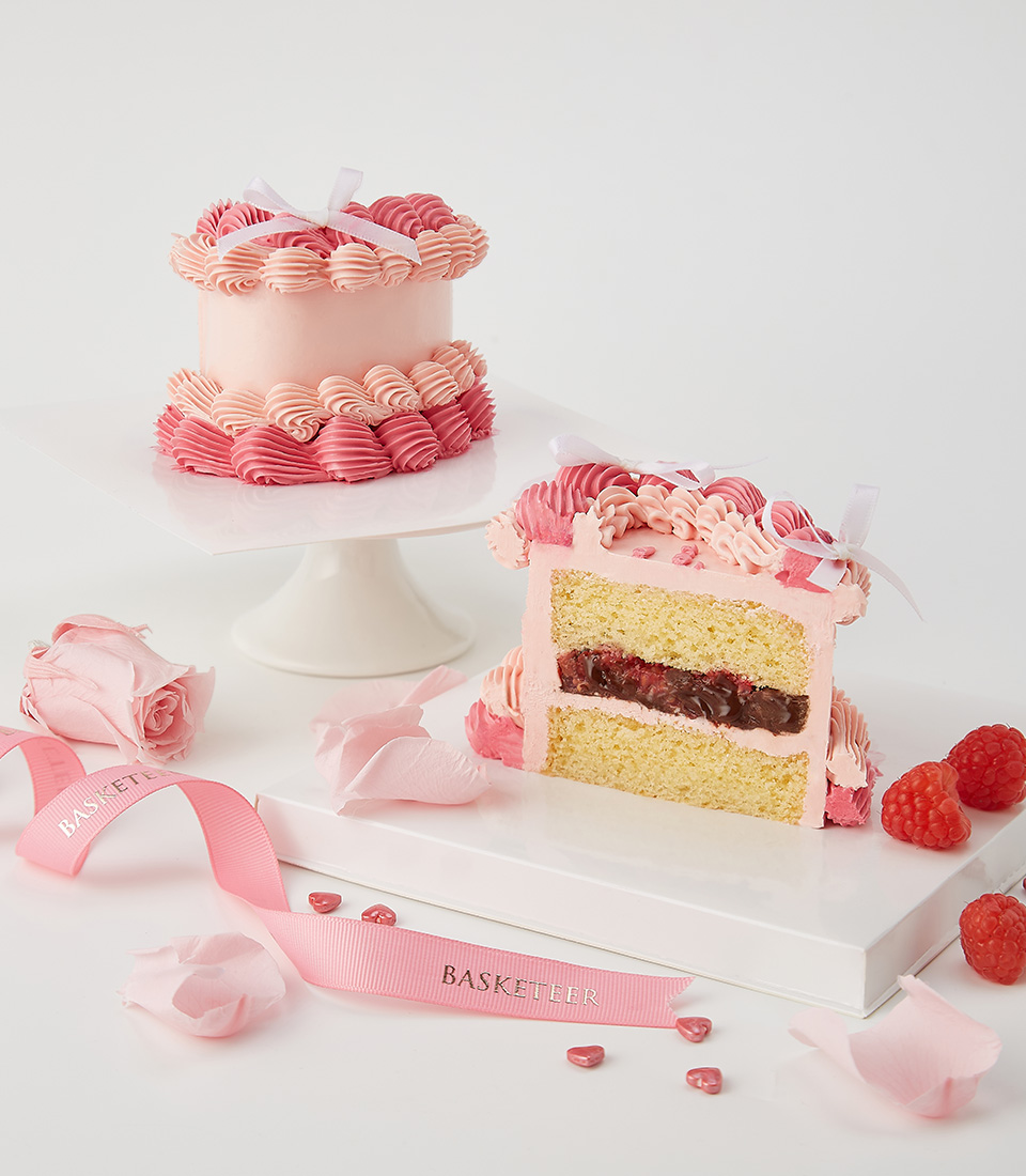 Close-up of a heart-shaped pink cake with intricate piped buttercream swirls, white bows, and “I Love You” lettering, perfect for romantic celebrations.