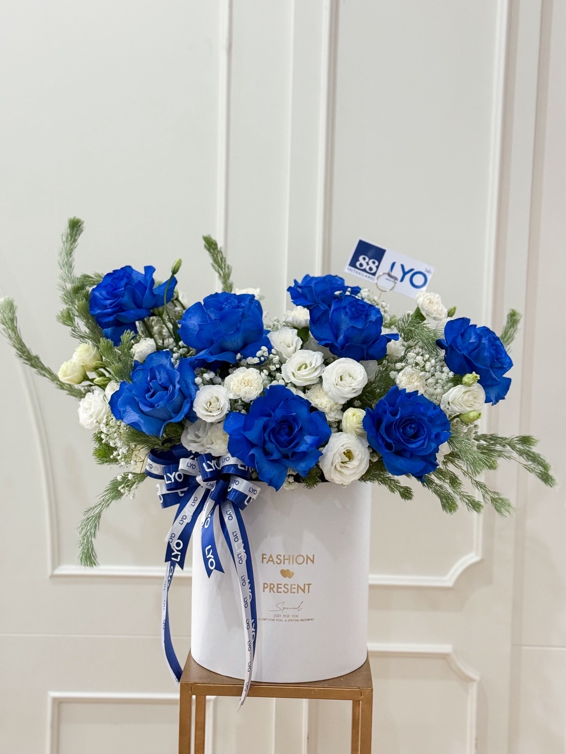 Luxury blue roses and white flowers arrangement in premium white round box with LYO ribbon, perfect for corporate gifts in Bangkok.