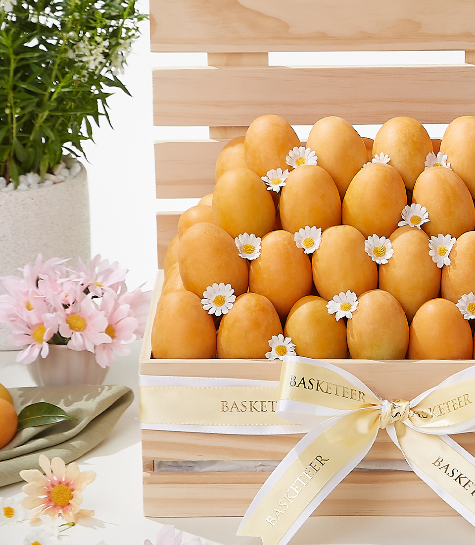 A beautifully arranged Mayongchid mango gift basket, featuring fresh golden-hued Mayongchid (Marian Plum) mangoes in an elegant wooden crate, adorned with white daisy flowers and a satin ribbon—a luxurious fruit gift for special occasions.
