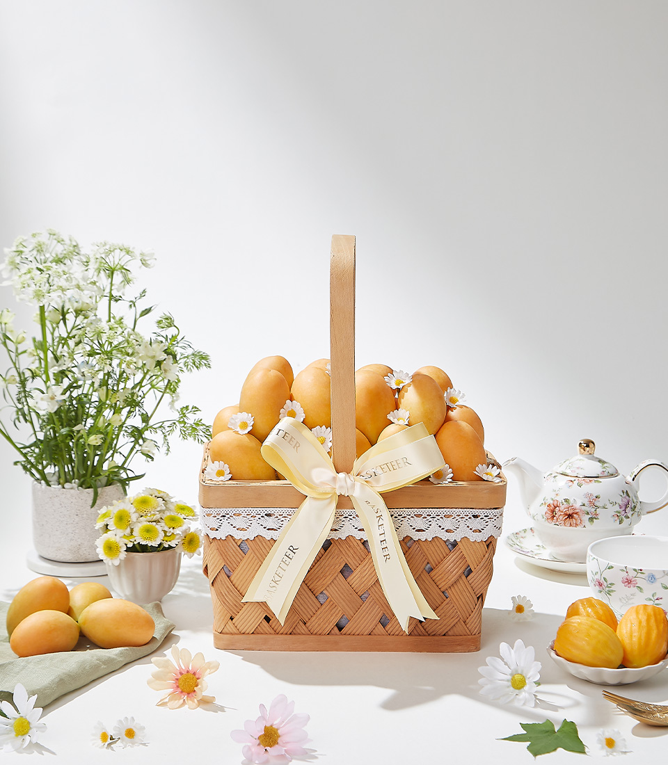 A beautifully handcrafted woven basket filled with premium Mayongchid (Marian Plum) fruit, elegantly decorated with a satin ribbon, exuding sweet tropical flavors and a delicate aroma.