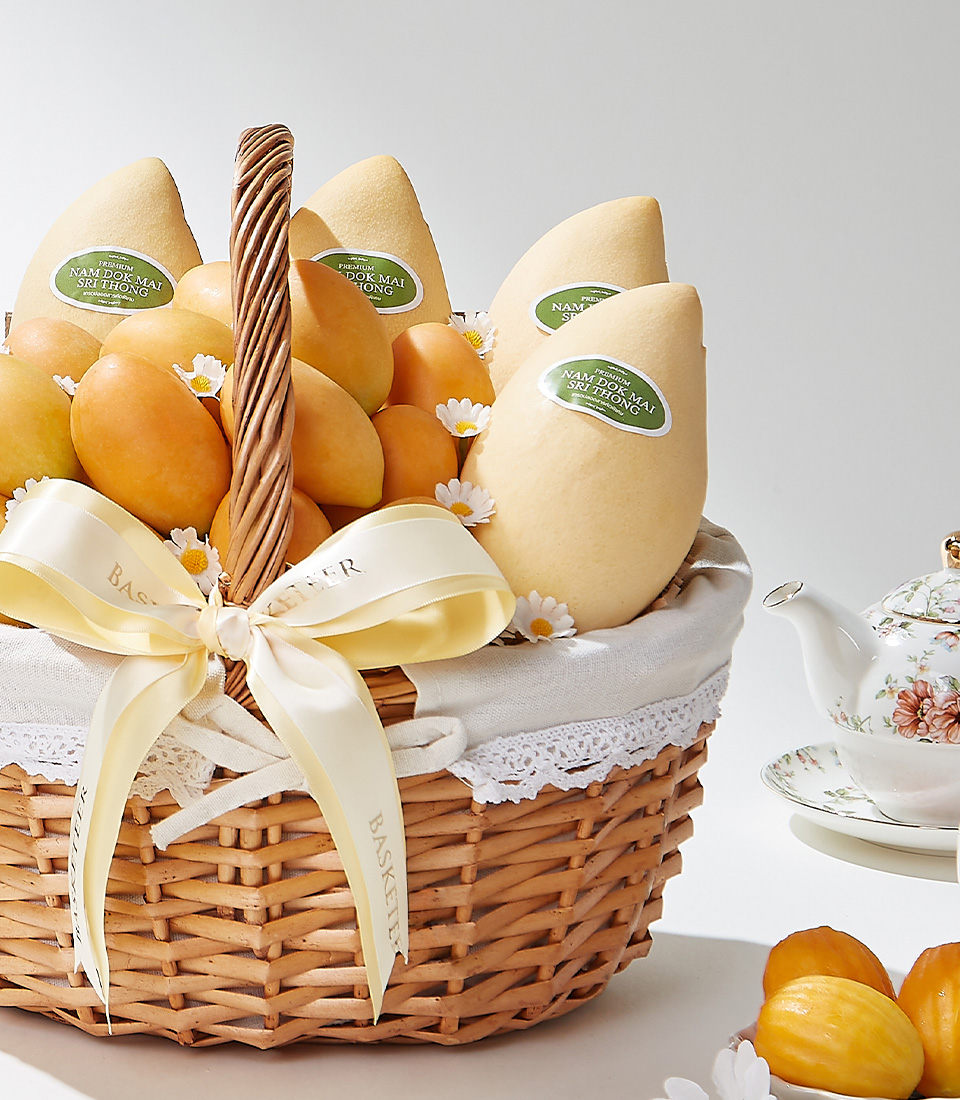 An elegant wicker basket filled with the finest Toon Klaow variety Mayongchid (Marian Plum) and premium Nam Dok Mai (Barracuda Mango), beautifully arranged with floral accents and a satin ribbon.