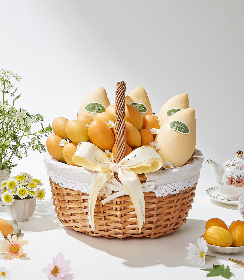An elegant wicker basket filled with the finest Toon Klaow variety Mayongchid (Marian Plum) and premium Nam Dok Mai (Barracuda Mango), beautifully arranged with floral accents and a satin ribbon.