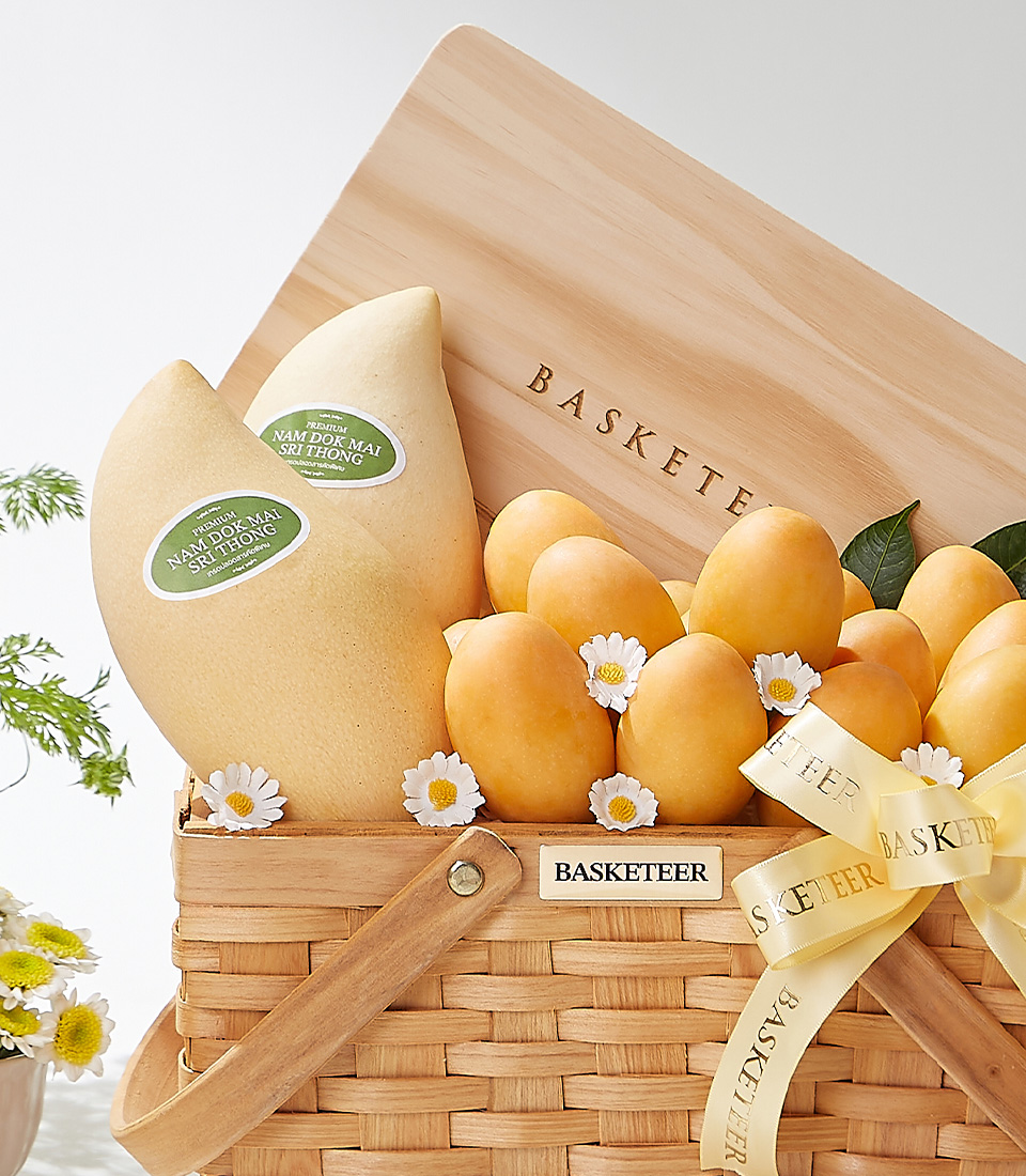 A wicker basket filled with premium Mayongchids of the Toon Klaow variety from Nakhon Nayok and Nam Dok Mai See Thong mangoes from Chachoengsao decorated with white daisies and a yellow ribbon