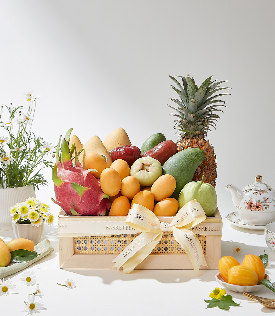 A wooden gift crate filled with premium Mayongchids from Nakhon Nayok, Nam Dok Mai See Thong mangoes, Keo Seowei green mangoes, rose apples, Kimju guava, red skin dragon fruit, pineapple, and green rose apples beautifully arranged with a cream ribbon