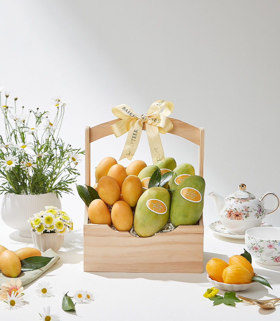 A wooden gift basket filled with premium Mayongchids from Nakhon Nayok and Ok-Rong mangoes from Damnoen Saduak beautifully arranged with green leaves and a yellow ribbon