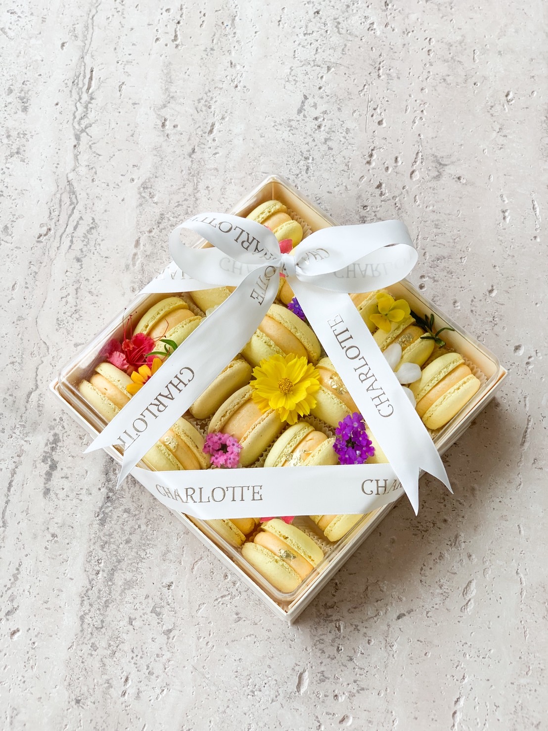Charlotte’s signature square box of yellow macaroons, adorned with edible flowers and a branded ribbon, evokes British charm in Bangkok.