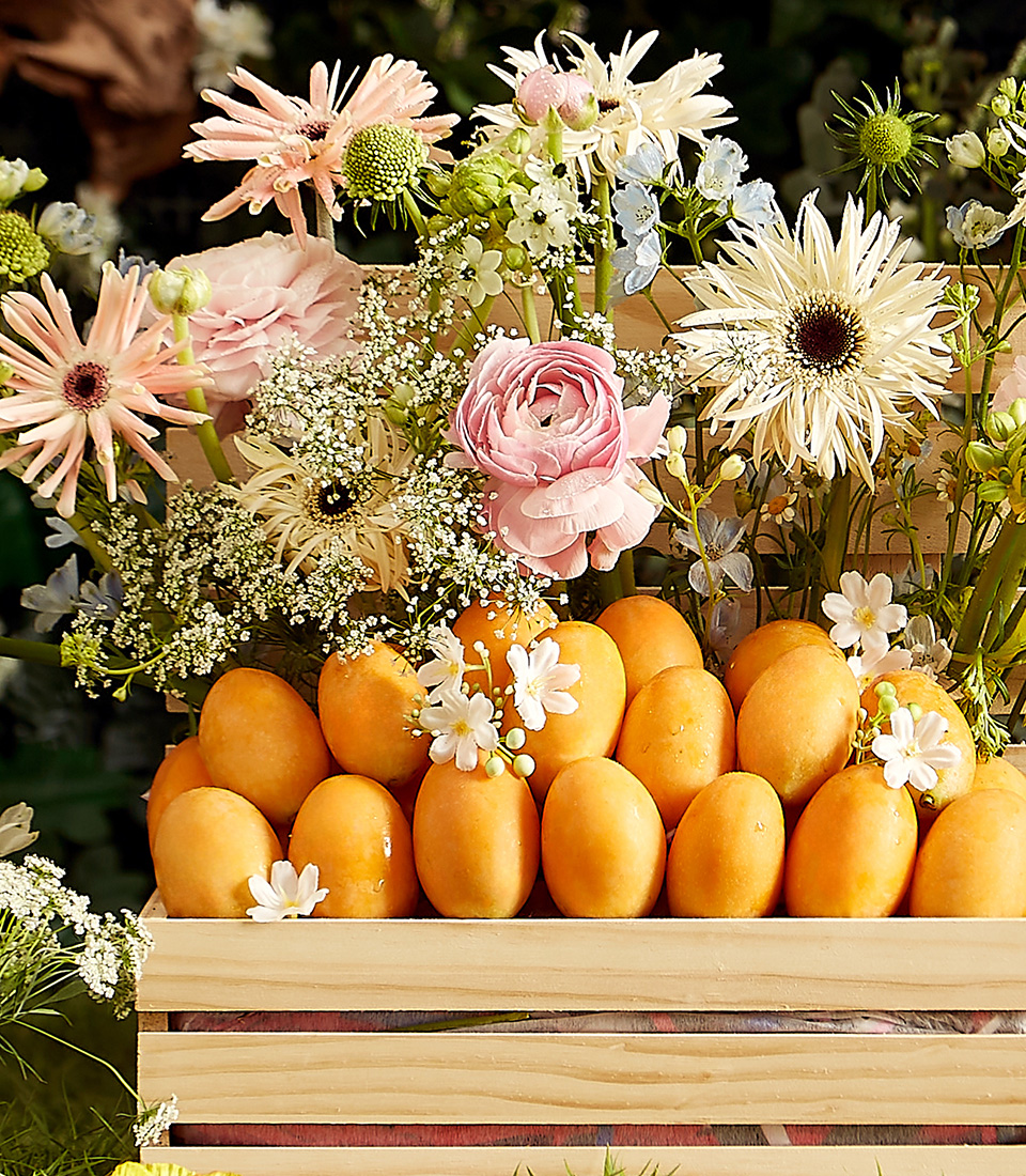Close-up of a stunning wooden crate filled with premium Mayongchids (Toon Klaow Variety Nakhon Nayok), elegantly arranged with fresh floral decorations.
