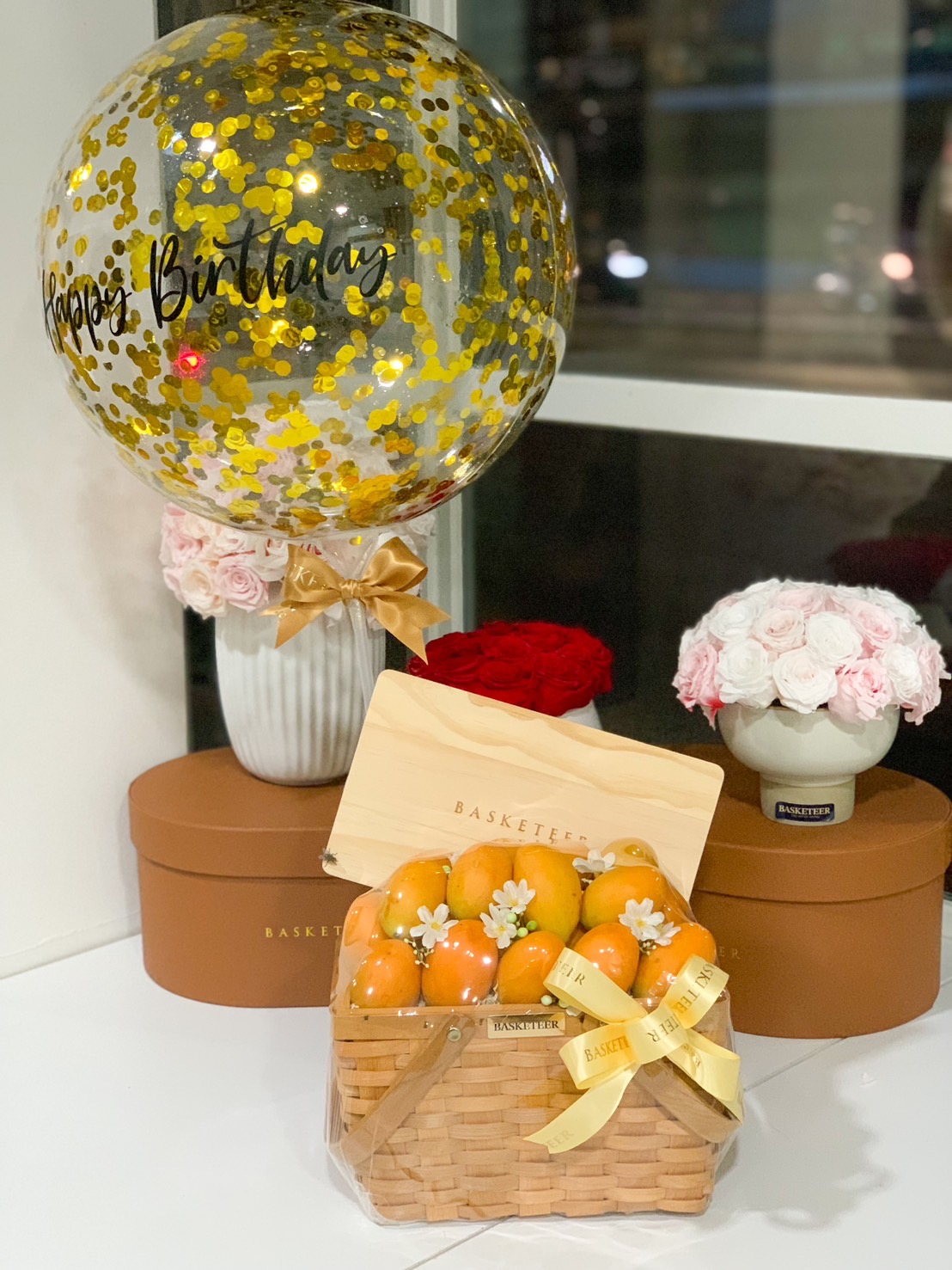 Birthday fruit gift basket with oranges and a gold confetti balloon.