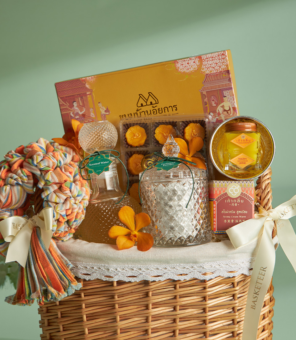 Close-up of a traditional Thai Songkran gift basket with scented water, sweet treats, and aroma cream in a wicker basket