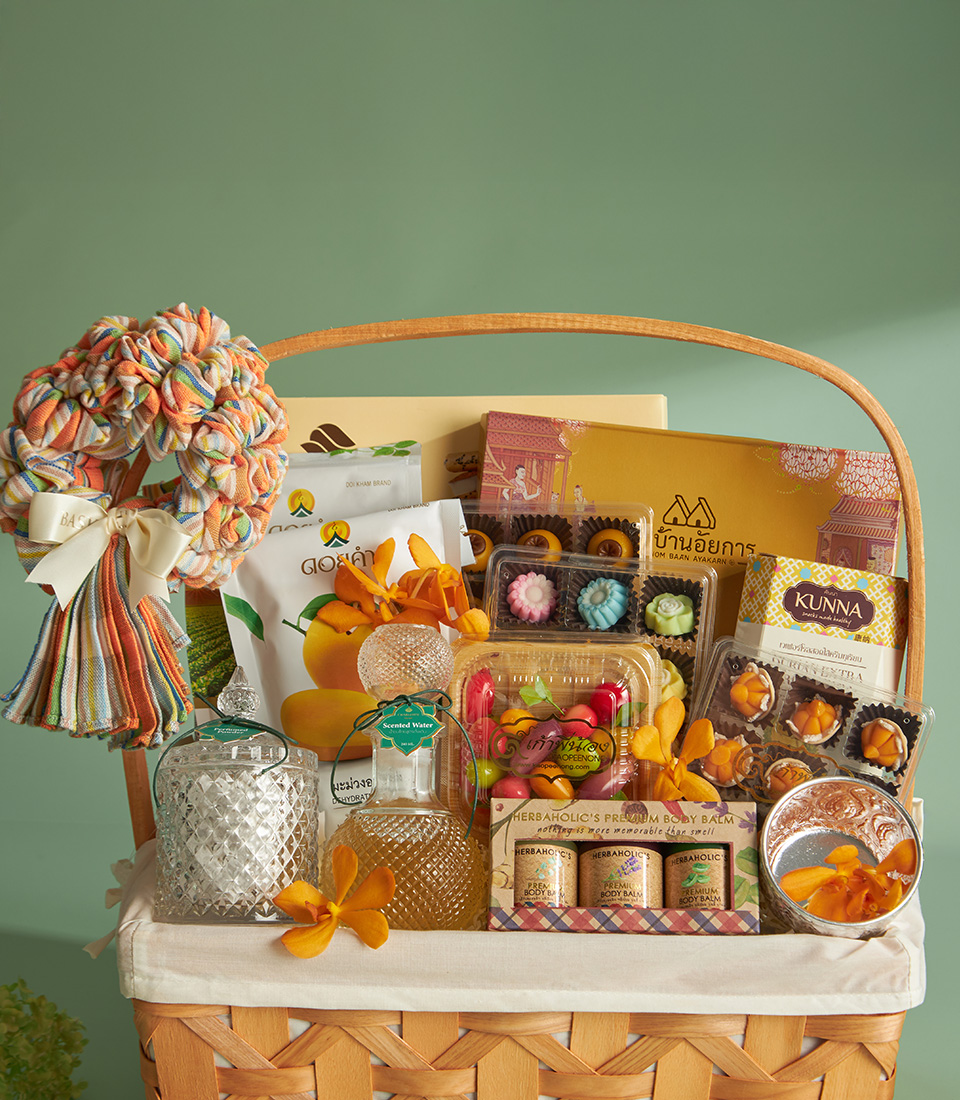 Close-up of a Traditional Thai Songkran gift basket with scented water, herbal balms, Thai sweets, dried mango, and crispy rolls