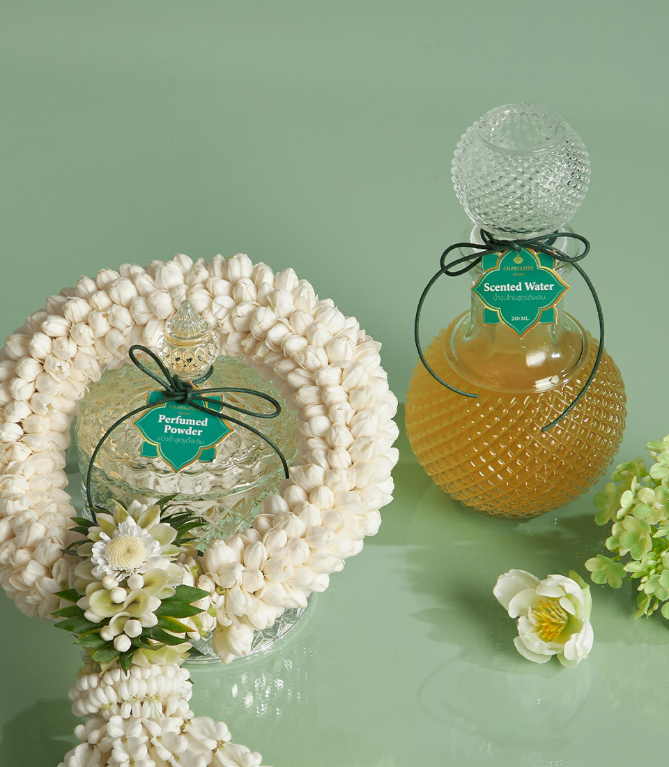 Close-up of a Thai scented water, powder perfume in glass jars, and white floral garland for Songkran rituals