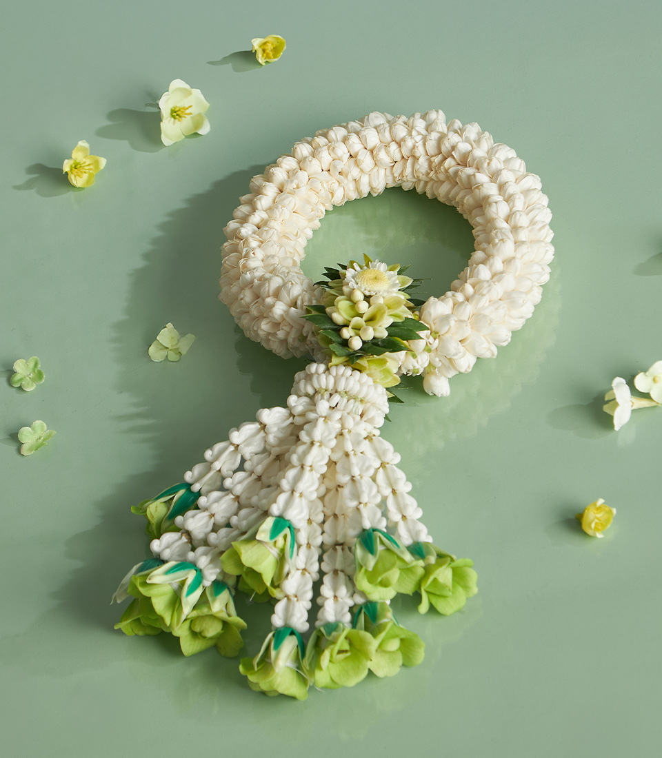 Traditional jasmine garland with green floral accent for Songkran celebration on pastel green background