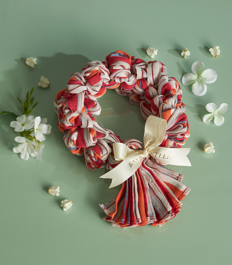 Red-striped Thai loincloth (Pha-Kao-Ma) garland with ribbon, arranged with white flowers on a pastel green background