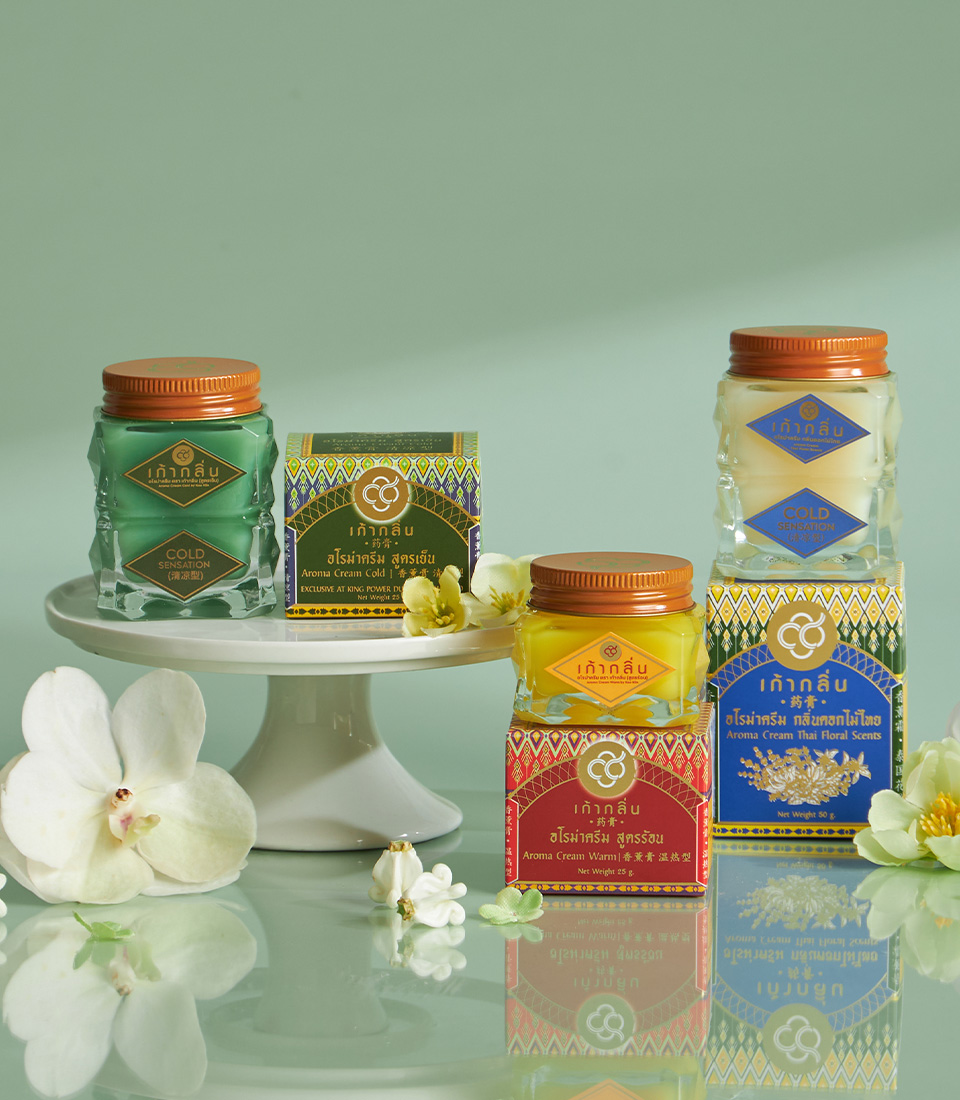 Set of Kaoklin aroma creams in colourful jars and boxes with floral decorations on a glass surface
