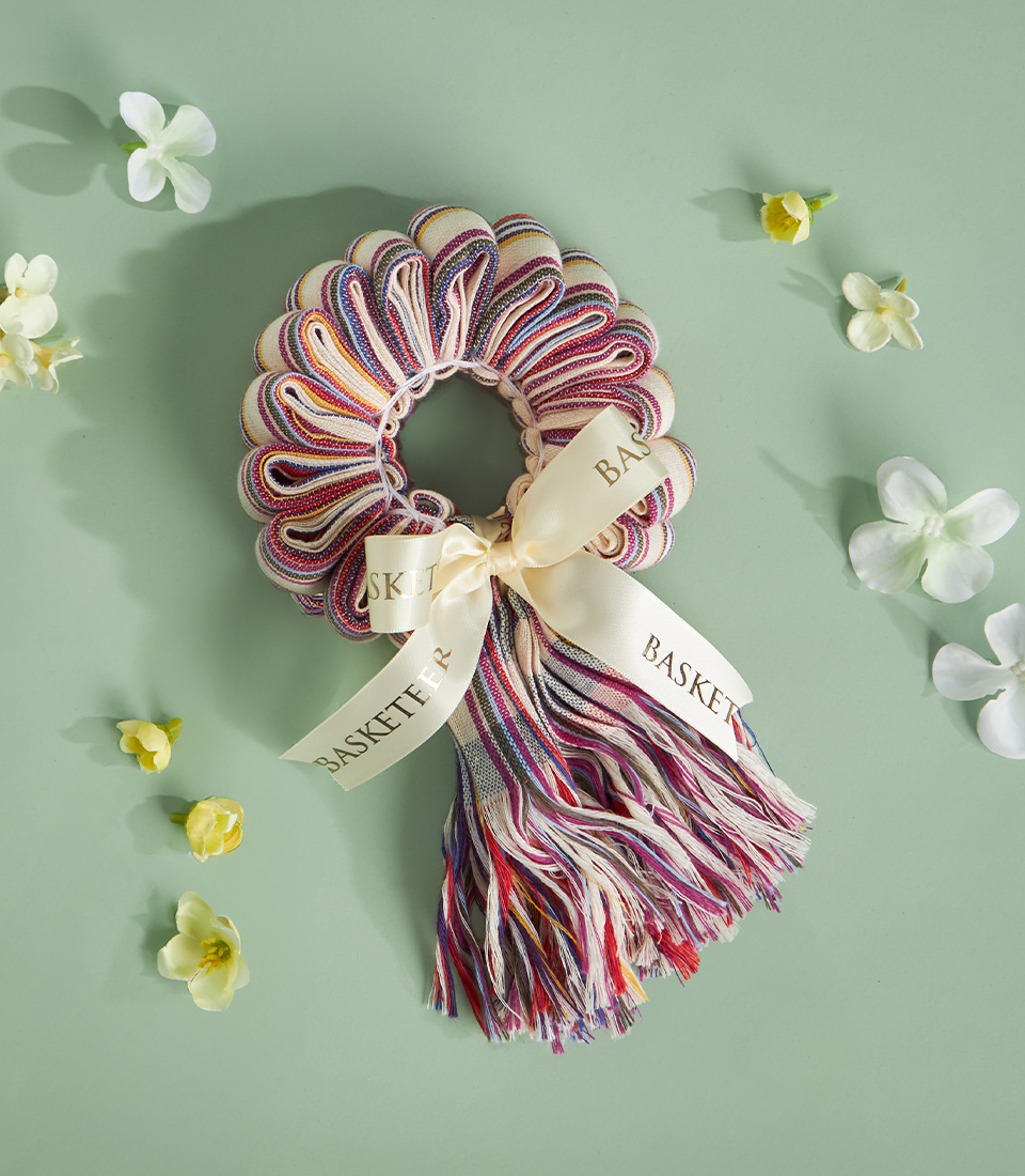 Multicolour Thai loincloth garland with pastel tones and ivory ribbon, laid on a soft green background