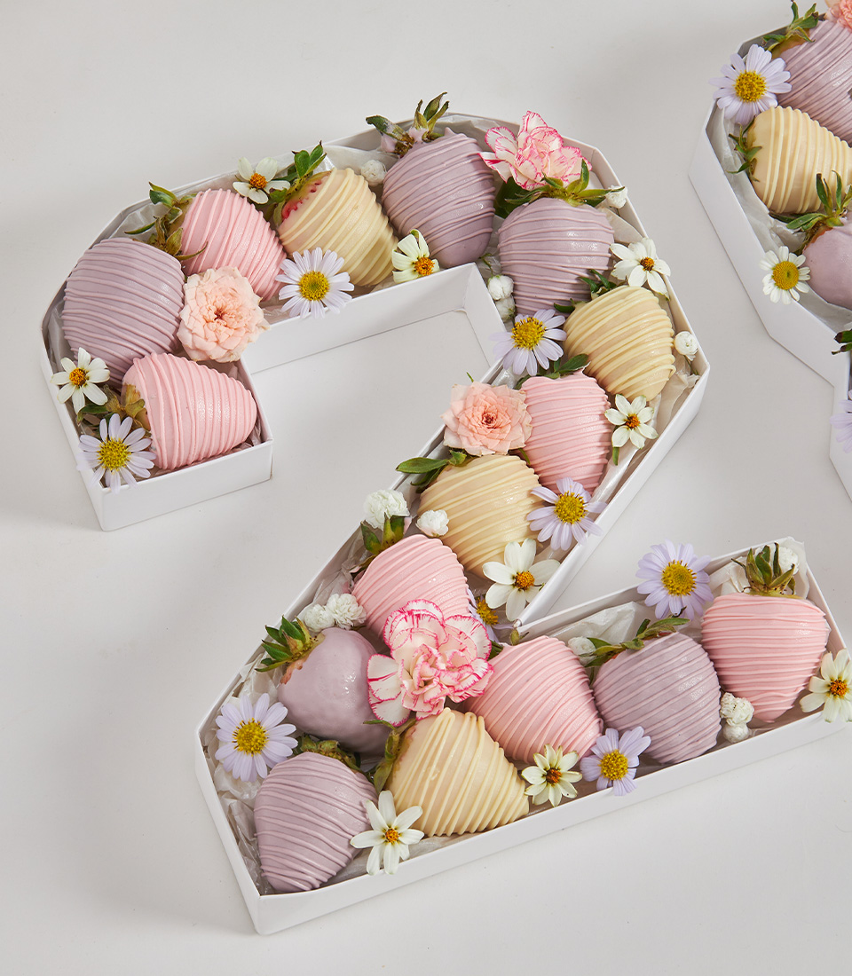 Close-up of number 2 gift box filled with pastel chocolate-covered strawberries and decorated with pink and white fresh flowers