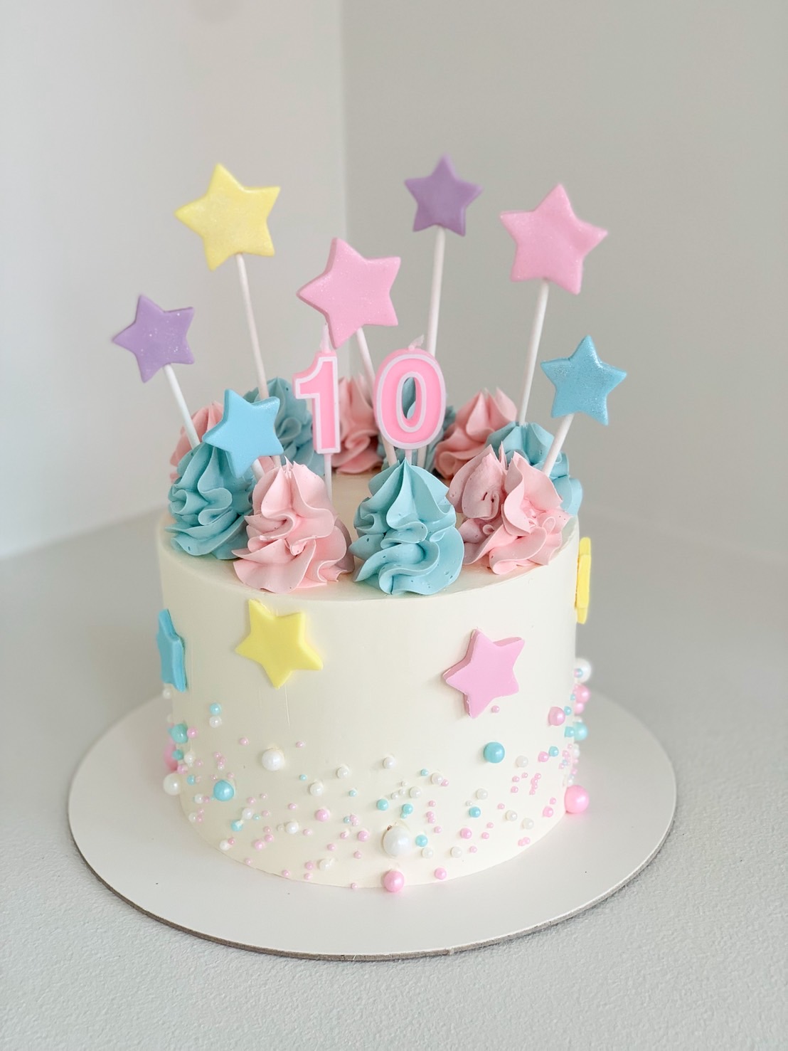 Pastel star birthday cake with pink number 10 topper, colourful stars and pastel buttercream decorations for kids.