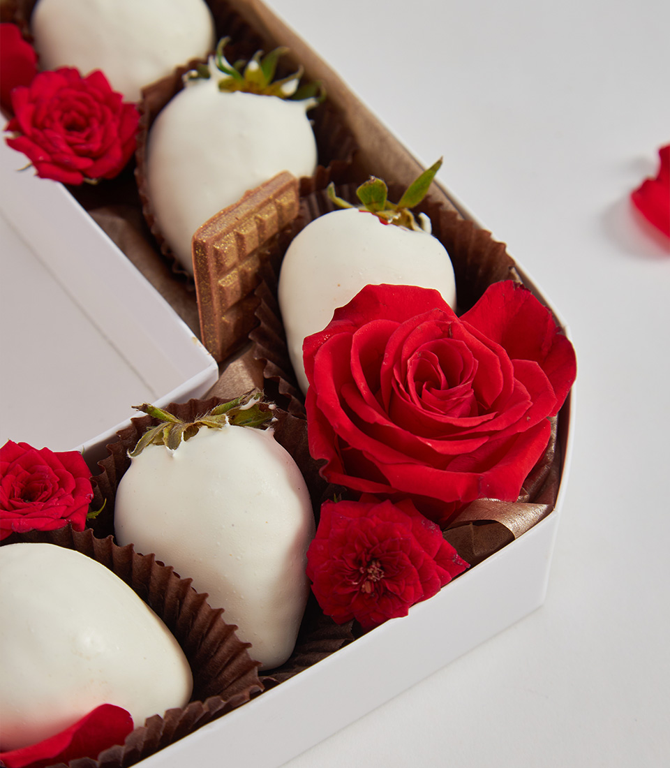 Close-up of white chocolate strawberries with red roses and chocolate wafer inside a number 0 gift box