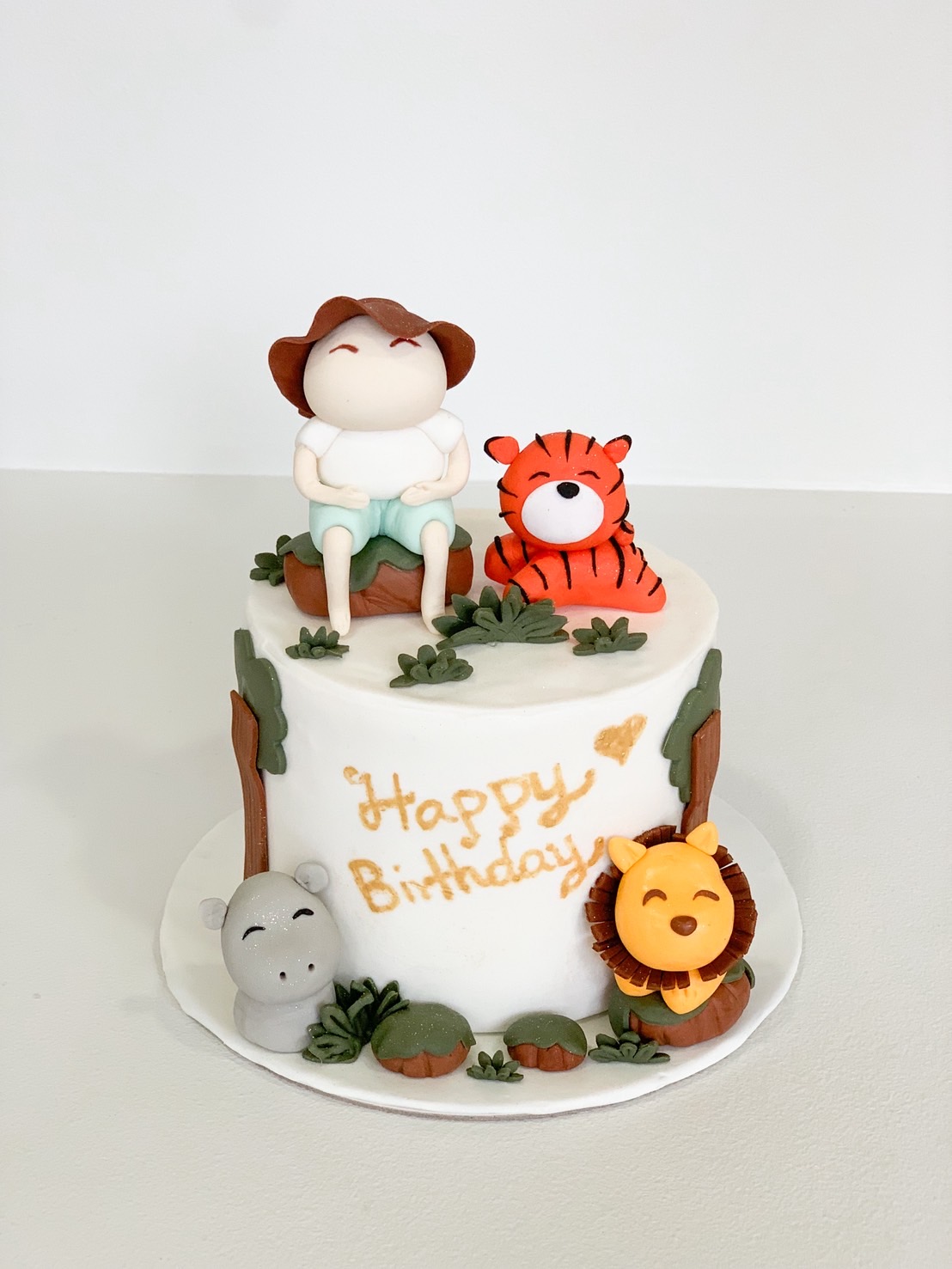 Jungle safari themed birthday cake decorated with fondant animals and a cute safari boy topper.