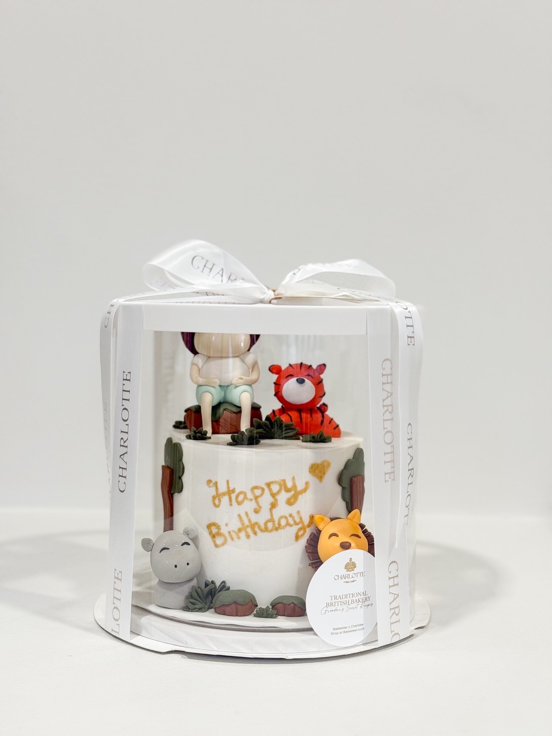 Jungle safari birthday cake in a clear gift box with fondant animals and a cute safari boy topper.