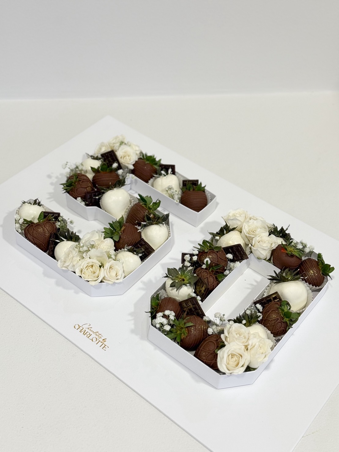 Chocolate covered strawberries arranged in number 50 box with fresh white roses for 50th birthday celebration.