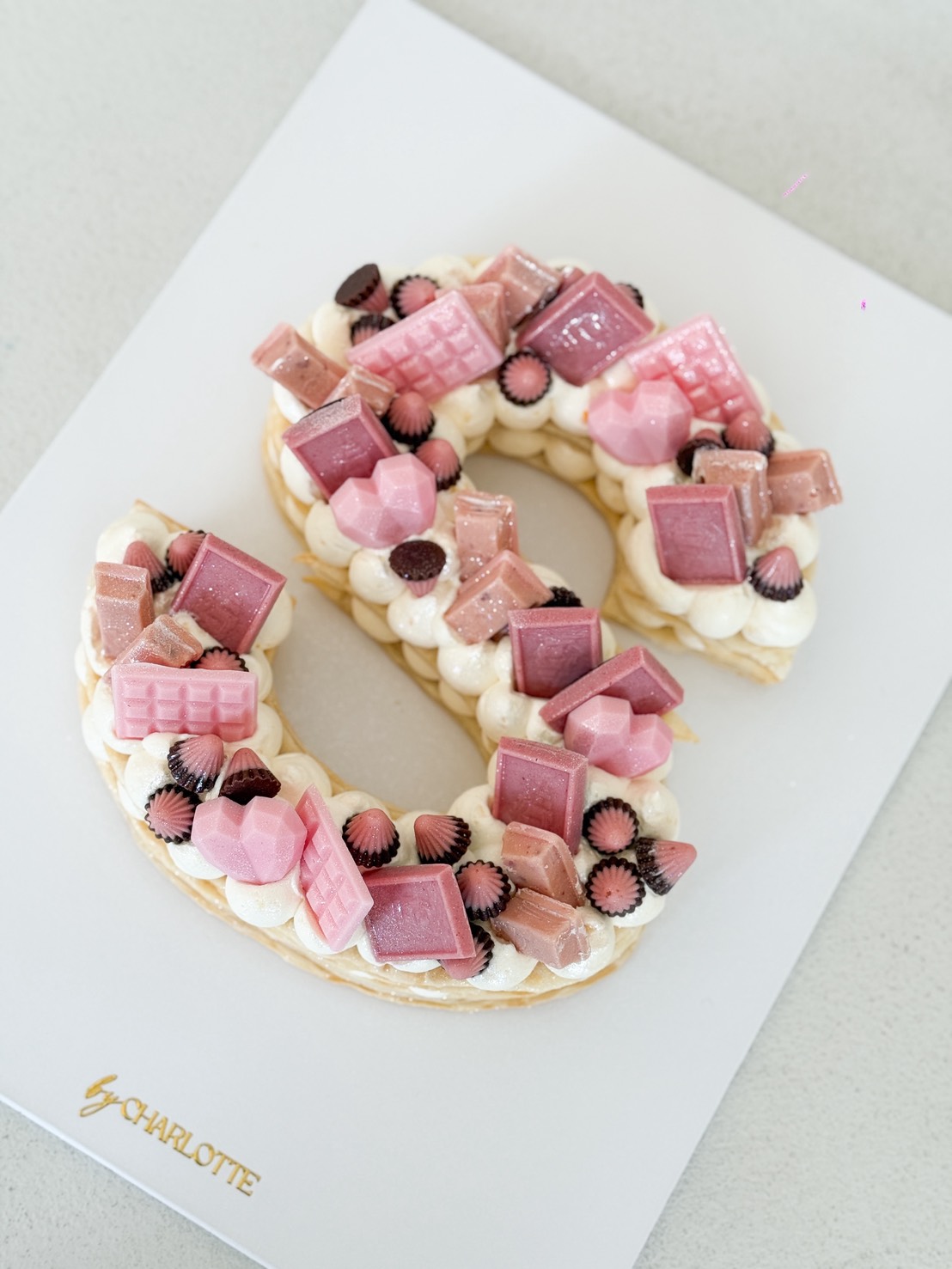 The Sweet Pink Puff Letter Cake is shaped like an 