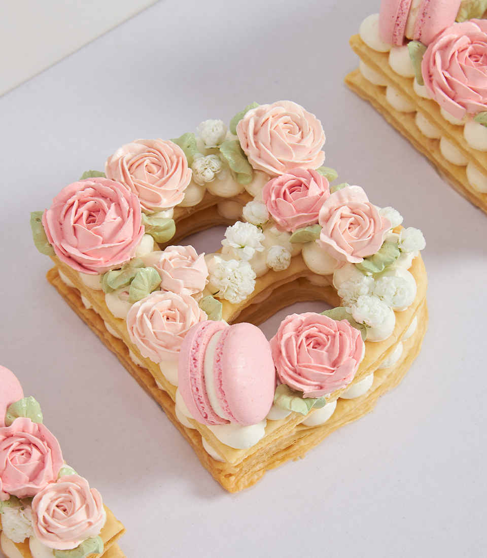 Letter B pie cake topped with soft rose piping and pink macaron