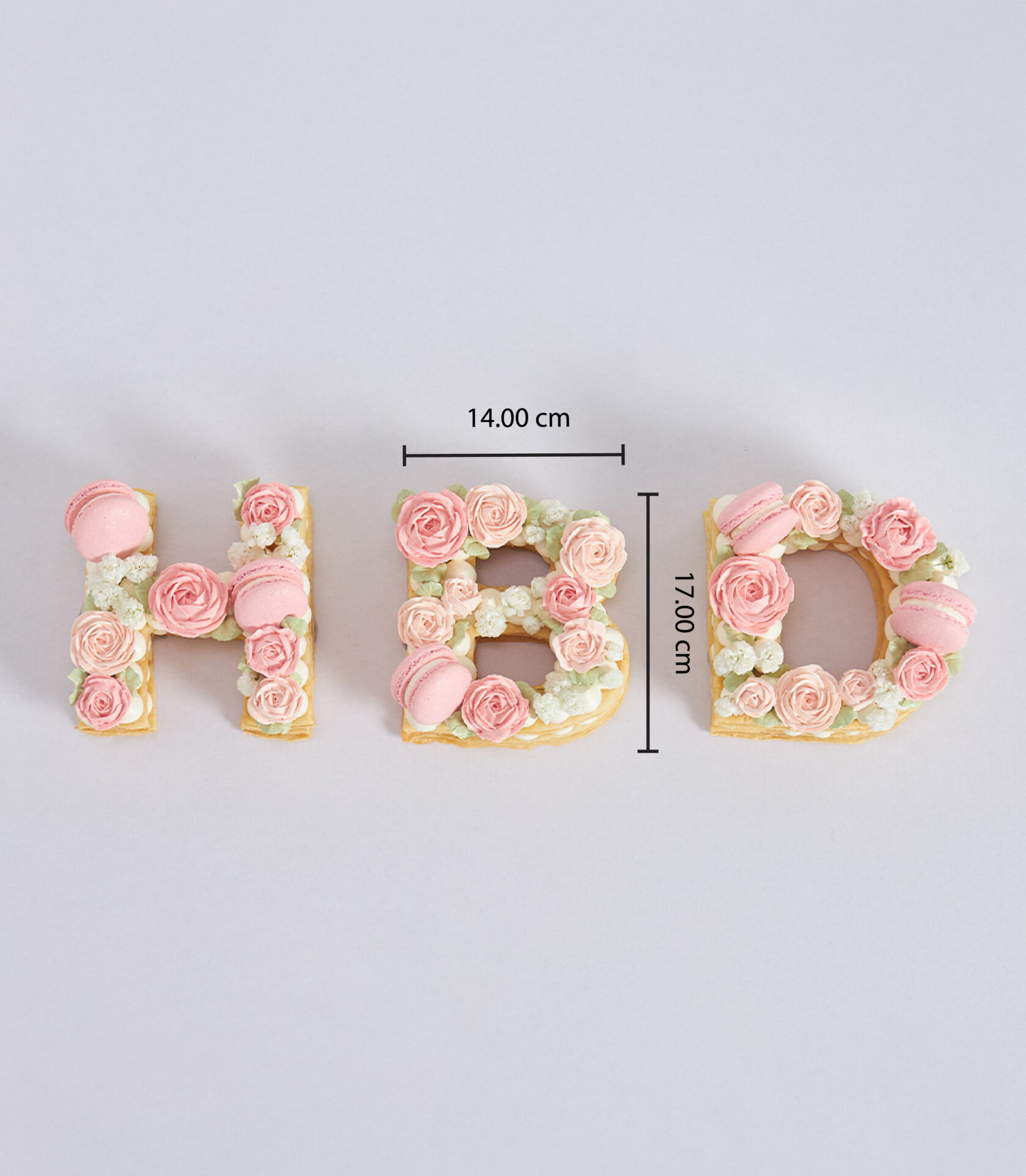 H and B letter-shaped pie cakes topped with rose buttercream and pink macarons