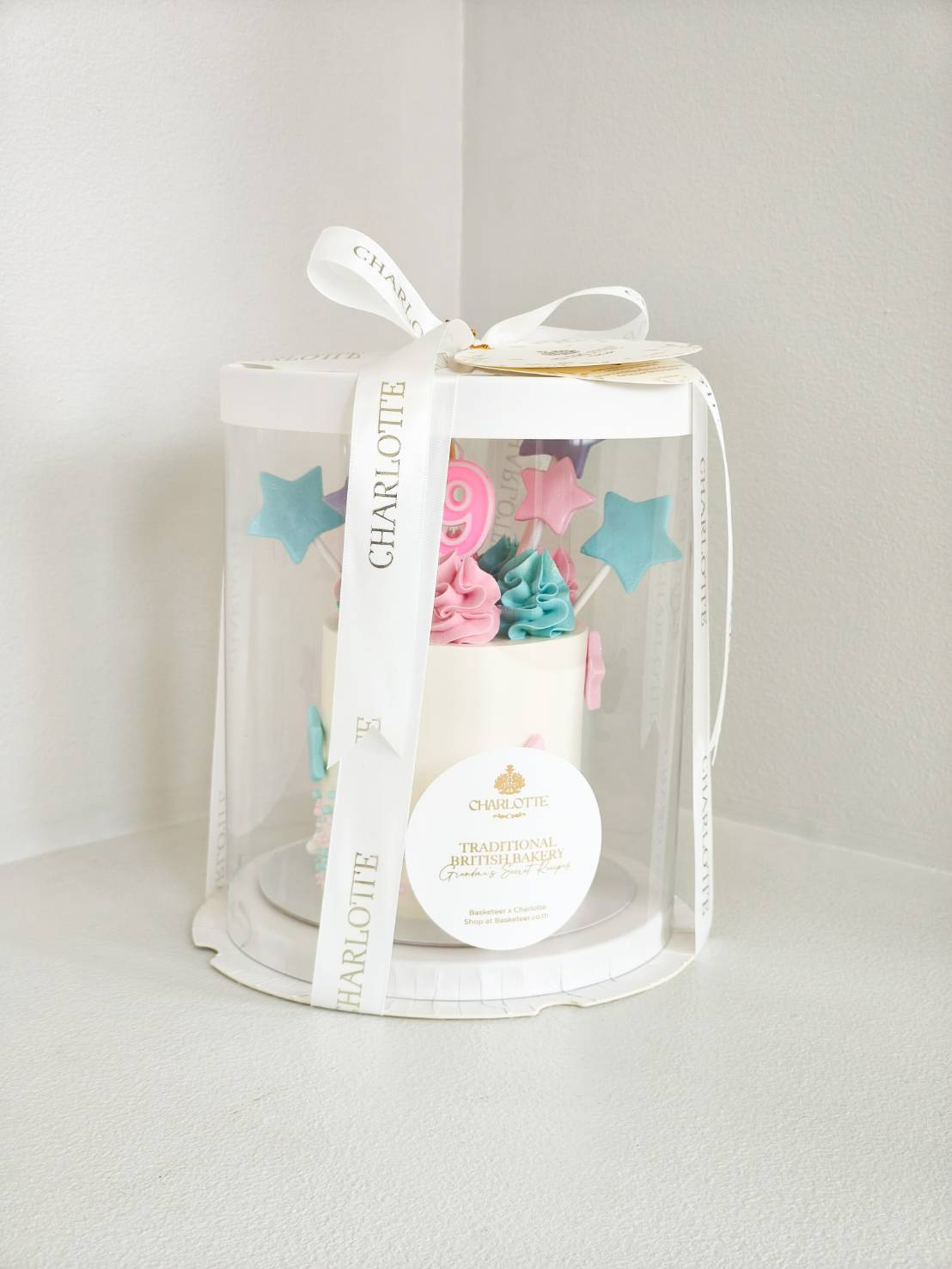 Pastel birthday cake with pink and blue star toppers in a premium Charlotte cake box