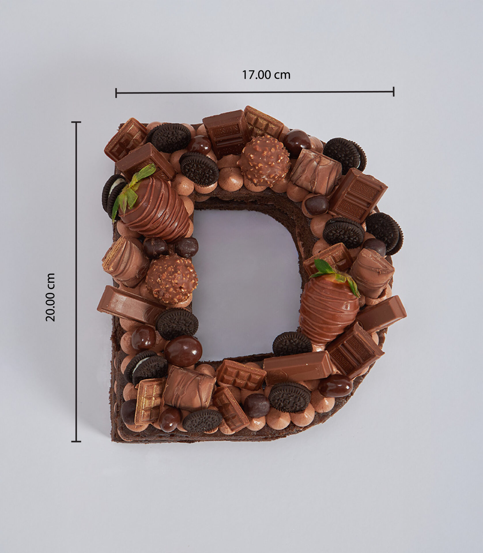 Chocolate letter cake topped with chocolate-dipped strawberries, mini Oreos, Ferrero Rocher, and assorted chocolate bars