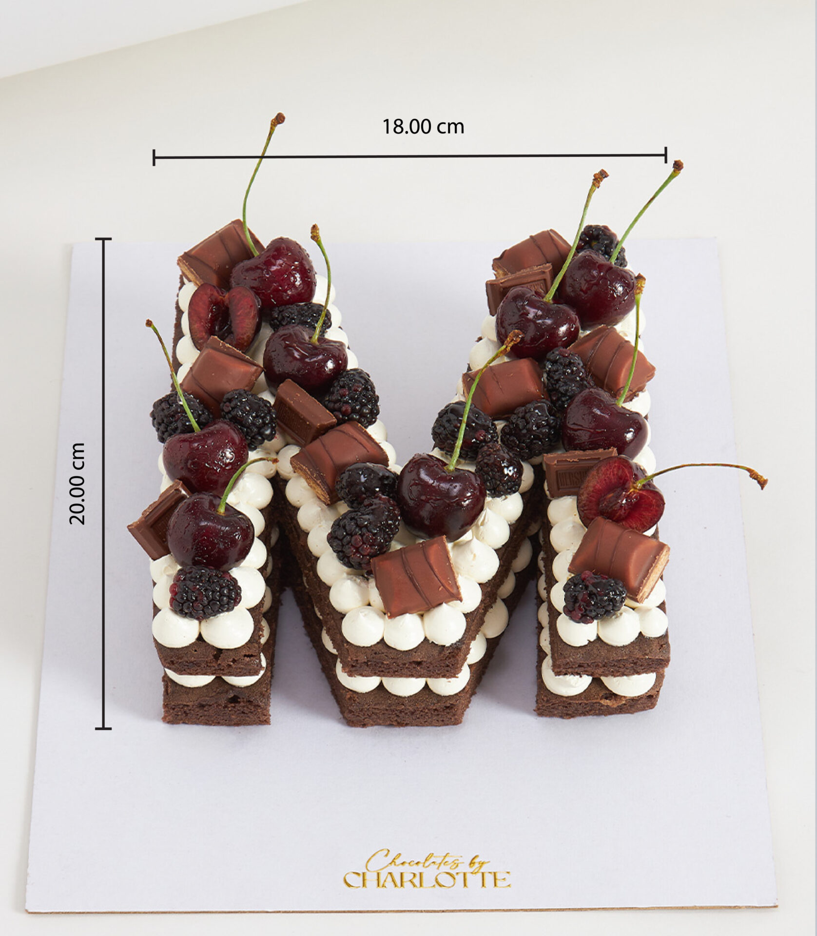 Chocolate sponge letter cake with cherries, blackberries, and assorted chocolates