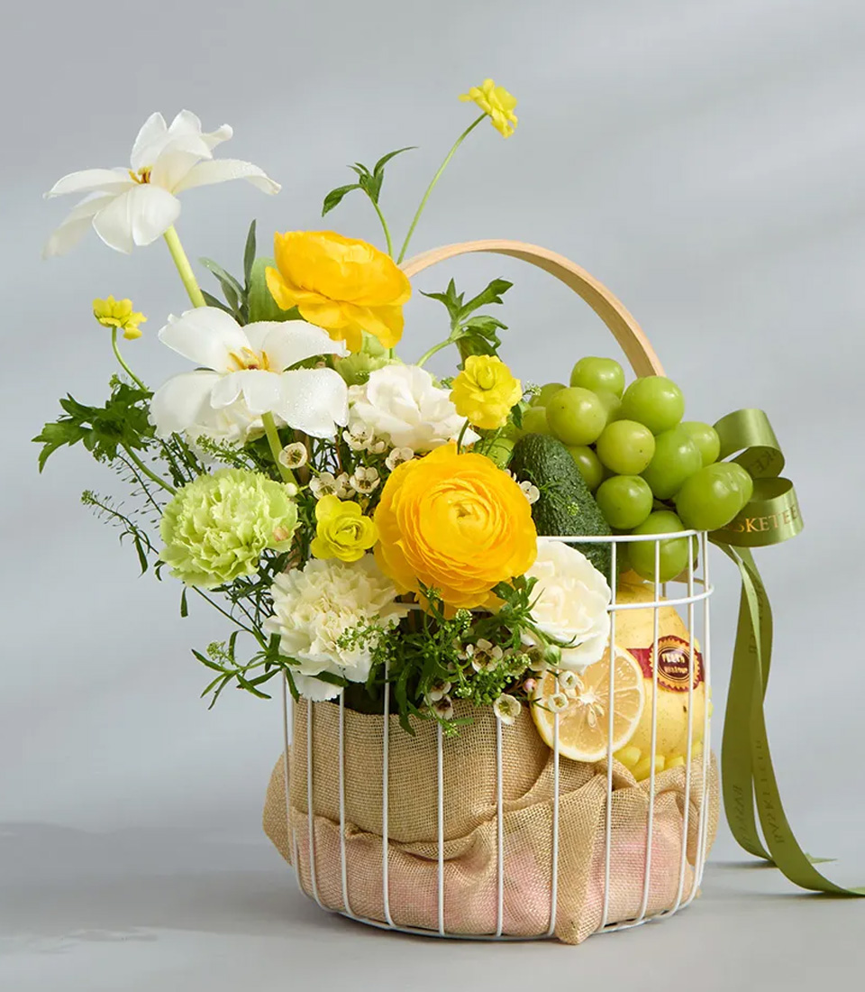 Fresh fruit and yellow-white flower basket in white wire container