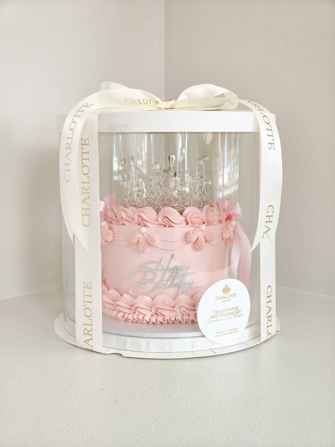 Elegant pink birthday cake with princess crown topper in luxury gift box.