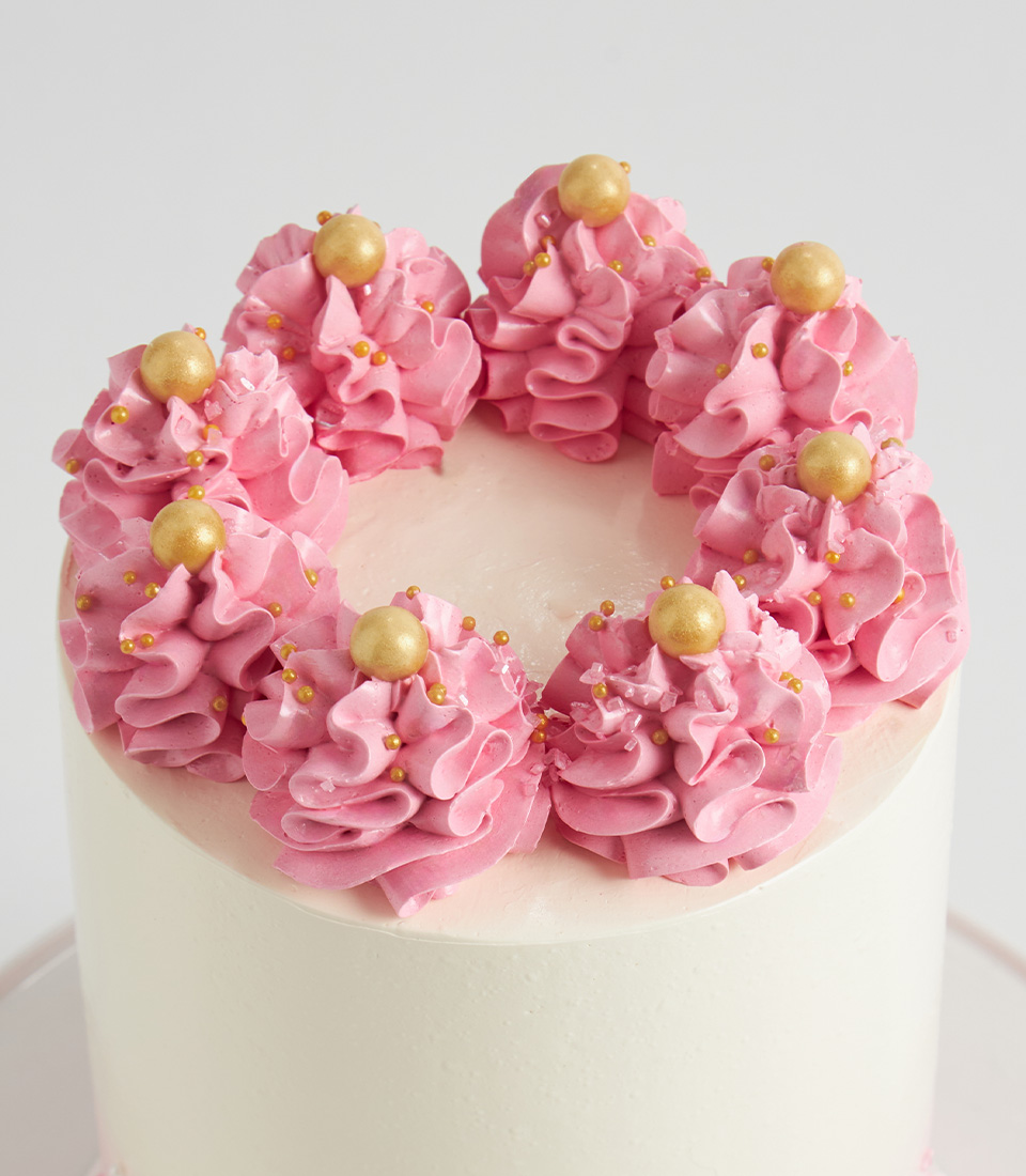 Close-up of pink buttercream crown swirls topped with gold edible pearls