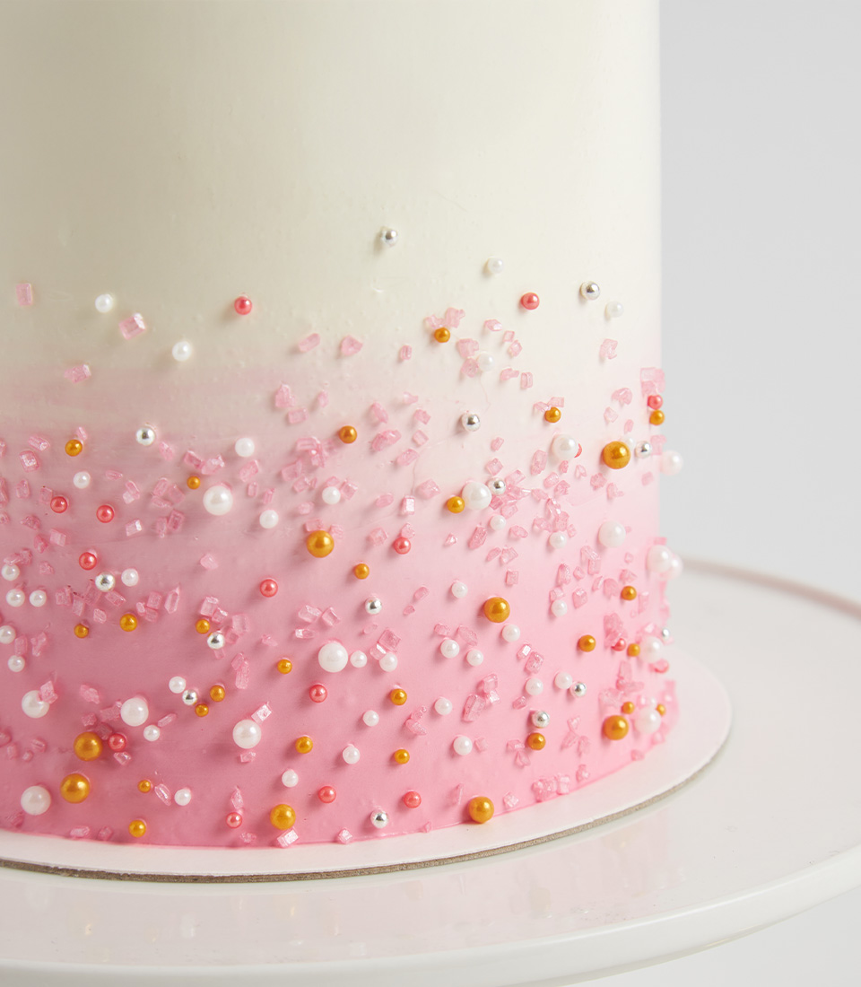Close-up of pink buttercream crown swirls topped with gold edible pearls