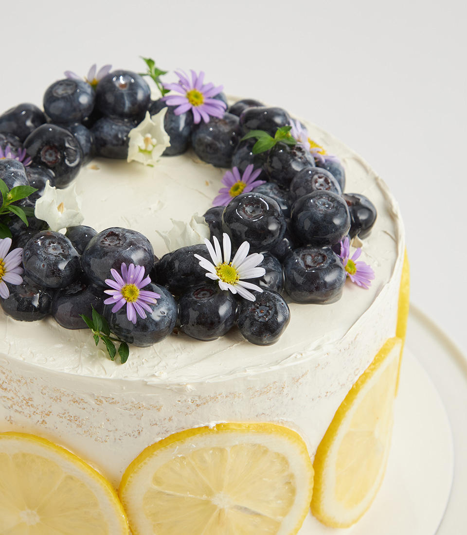 Close-up of blueberry and lemon cake topped with edible flowers and fresh fruit