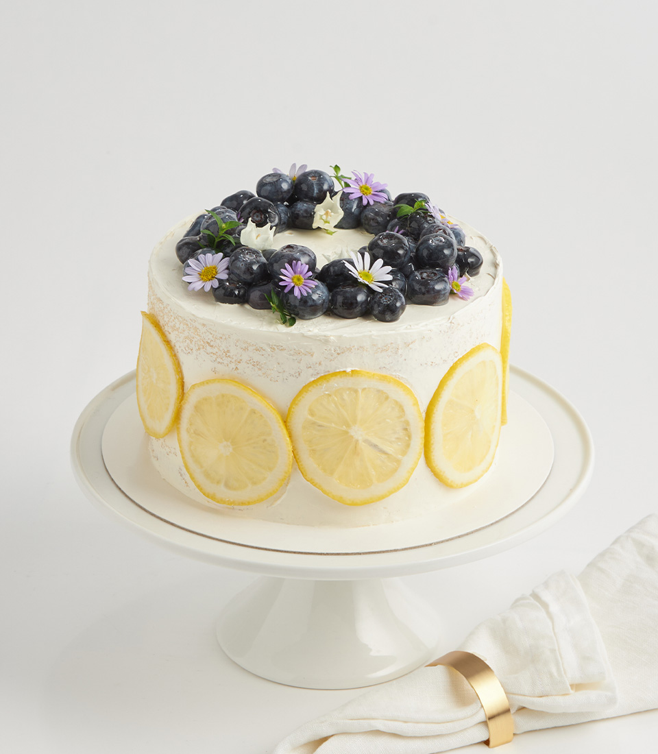 Lemon sponge cake with blueberries, lemon slices, edible flowers, and buttercream