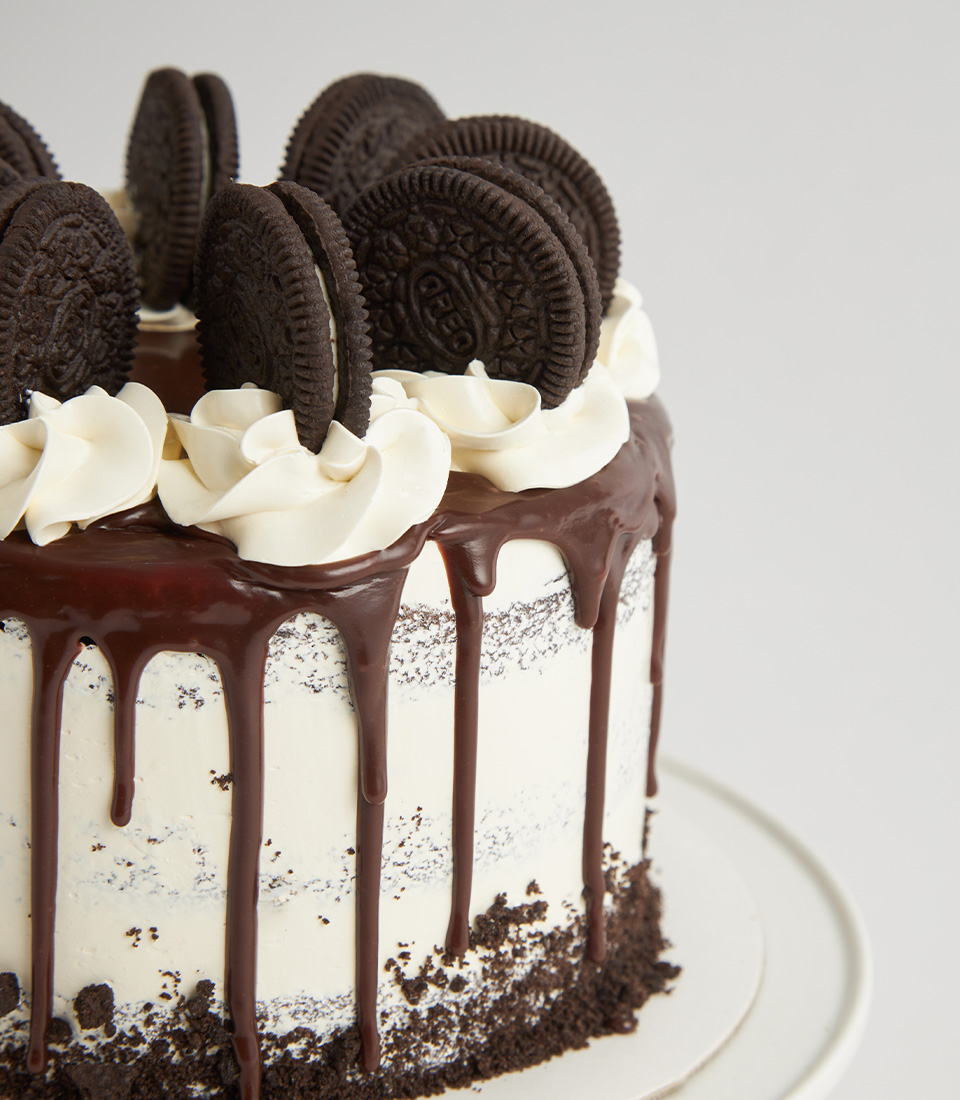 Close-up of Oreo cake with chocolate drip, buttercream swirls, and crushed cookies