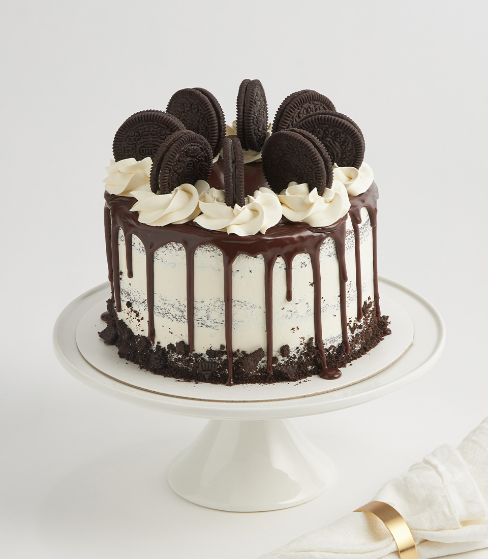 Chocolate drip cake topped with Oreo cookies, buttercream swirls, and crushed cookies