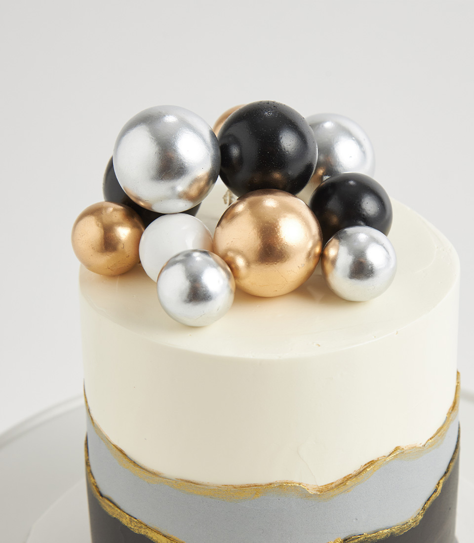 Close-up of luxury cake with black, gold, silver, and white metallic spheres