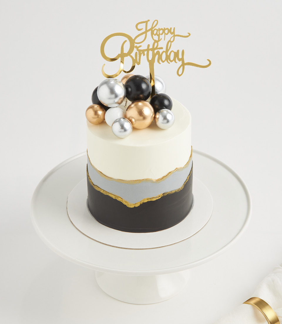 Close-up of luxury cake with black, gold, silver, and white metallic spheres