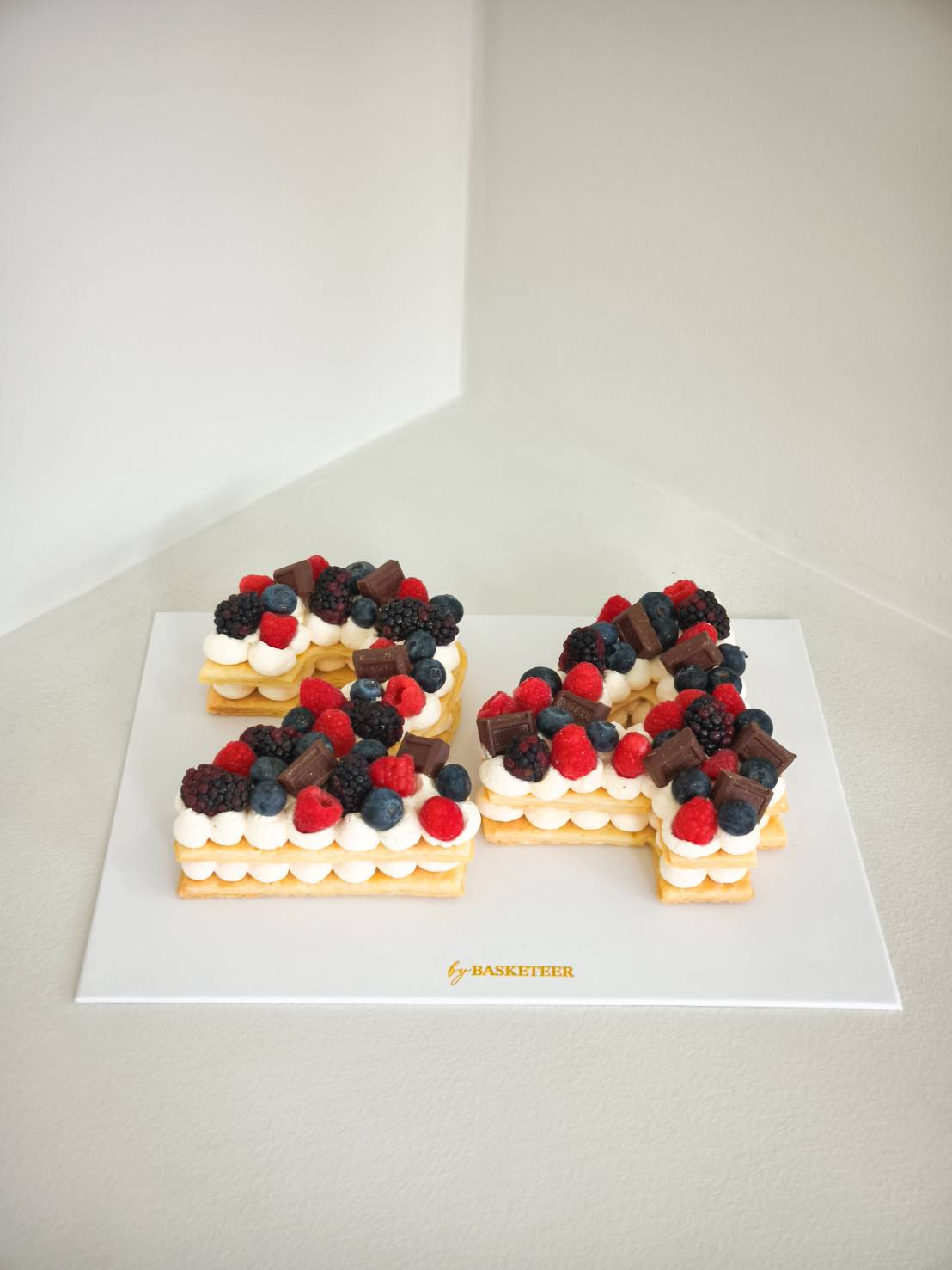 Celebrate with a Charlotte cake in the shape of 24, adorned with fresh berries and chocolate, by Basketeer luxury hampers Bangkok.