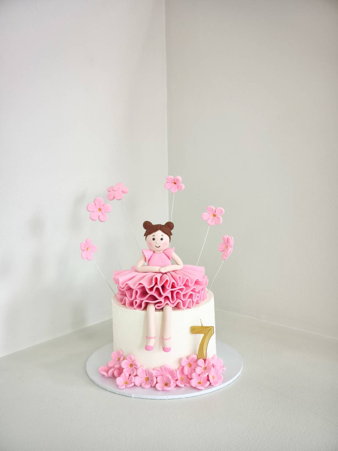 Princess themed pink birthday cake with fondant girl topper and flower decorations